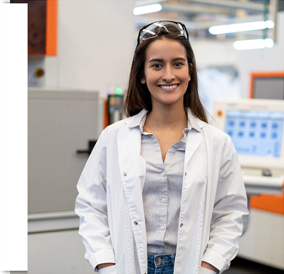 Female employee with lab coat and safety glasses in lab