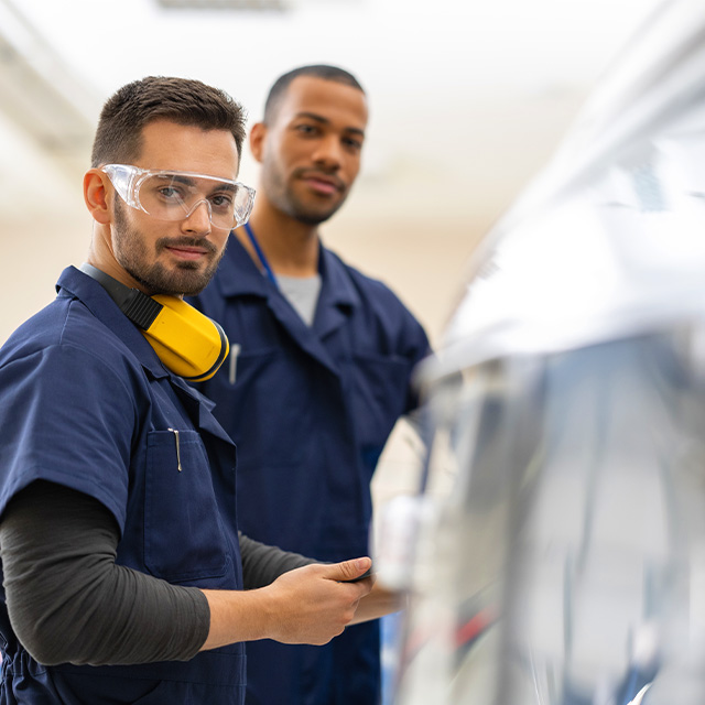 Two male maintenance employees looking at camera