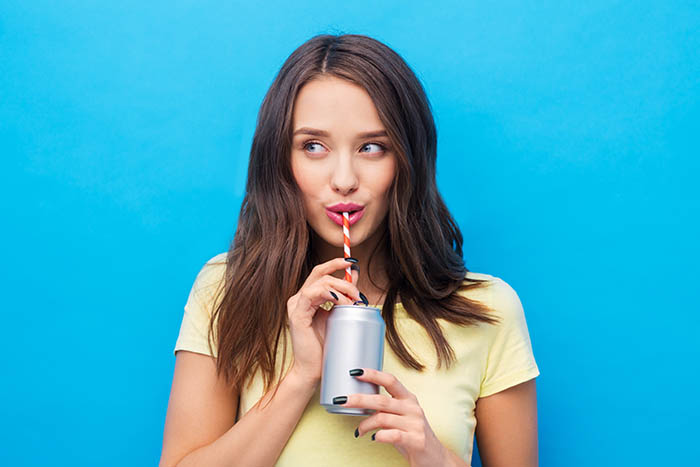 woman drinking from a can with a straw